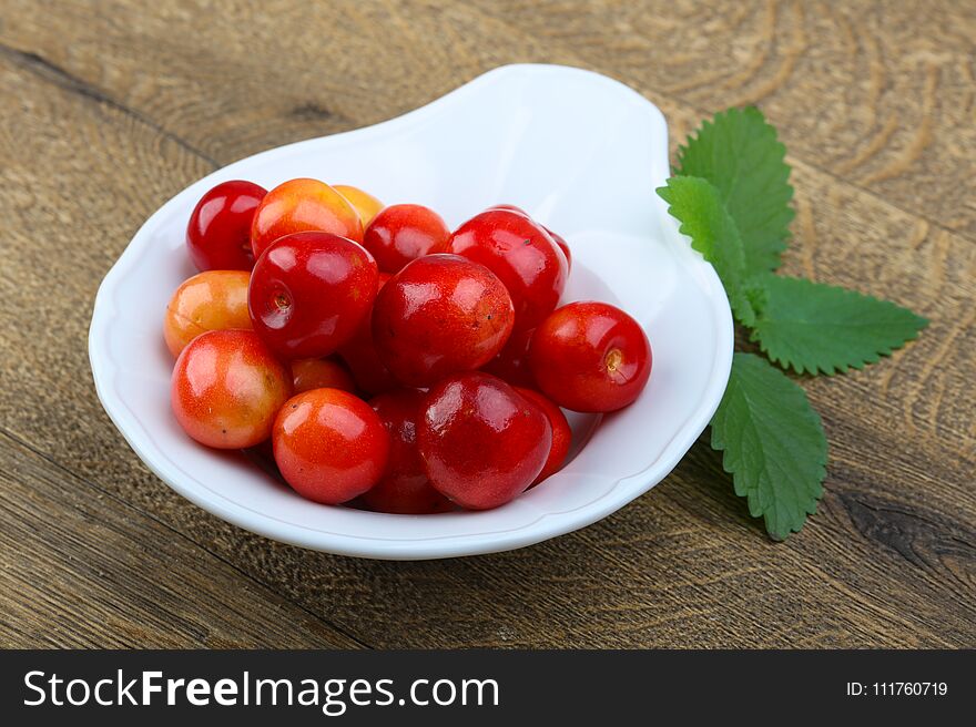 Sweet cherry in the bowl on wood background