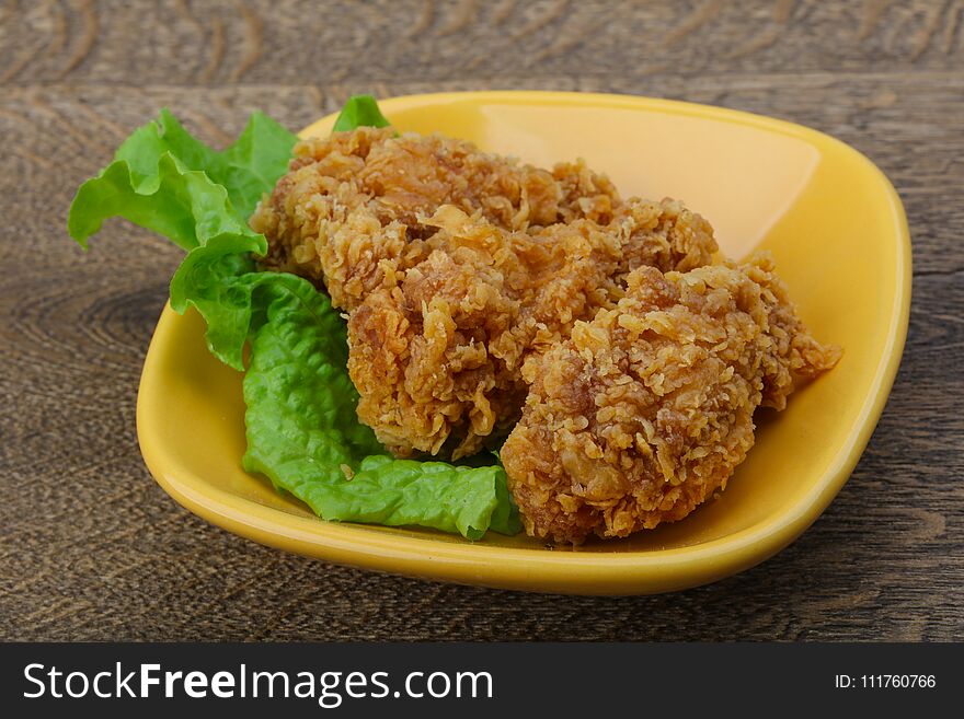 Crispy chicken wings with salad leaves on wood background