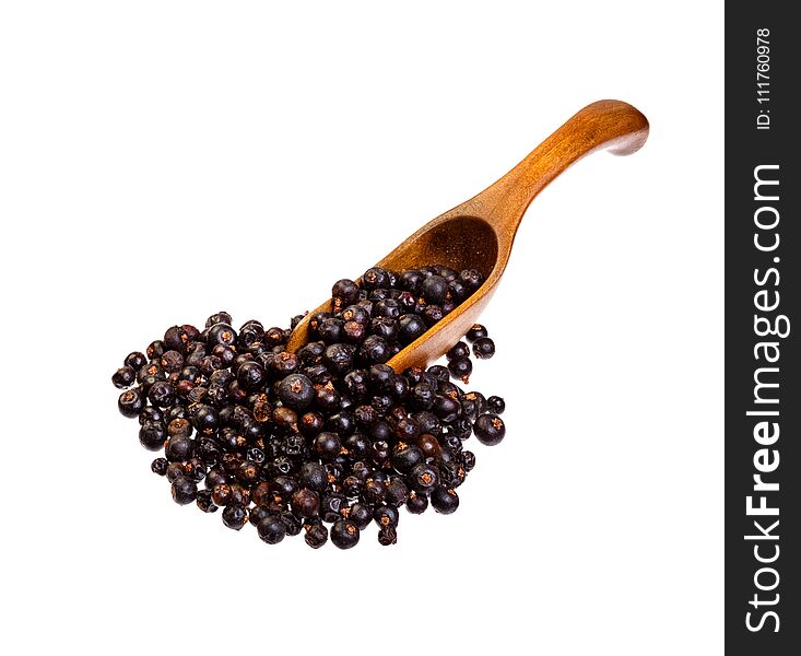 Dried Juniper berries on the wooden spoon. High resolution photo.