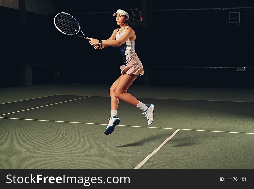 Female Tennis Player In Action In A Tennis Court Indoor.