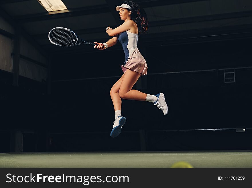 Female Tennis Player In A Jump On A Tennis Court.