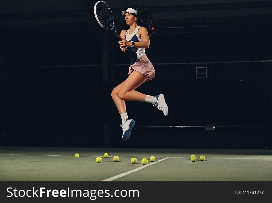 Female tennis player in a jump on a tennis court.