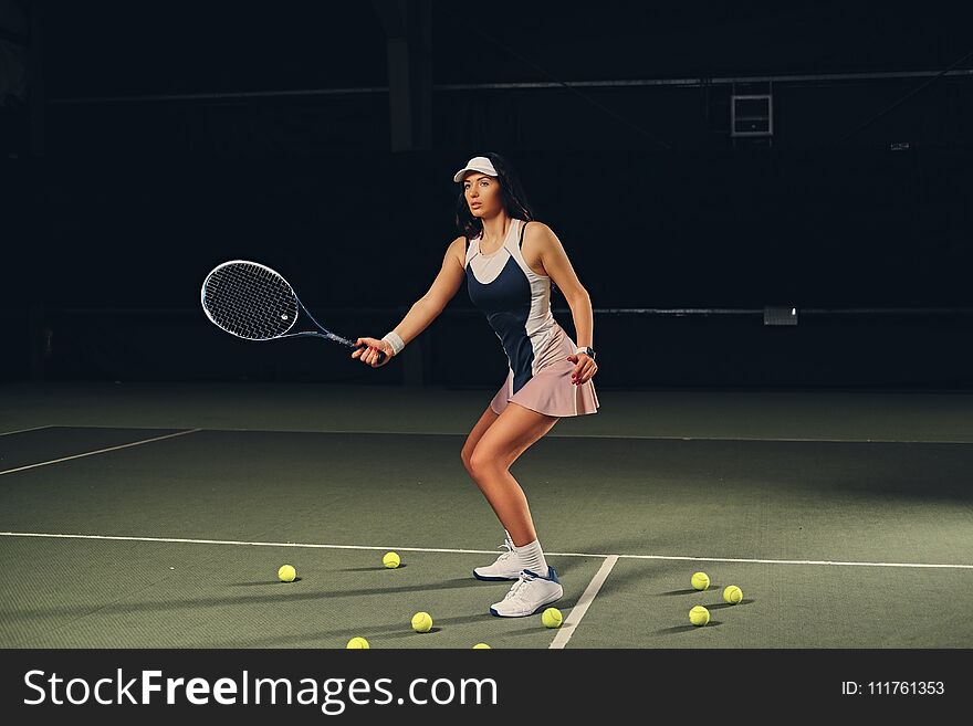 Female tennis player in action in a tennis court indoor.