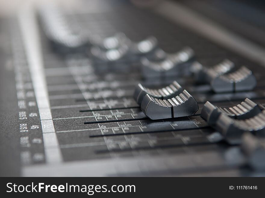 A industry studio mixing console. Close up makro photo of volume faders in grey with soft bokeh background. A industry studio mixing console. Close up makro photo of volume faders in grey with soft bokeh background.