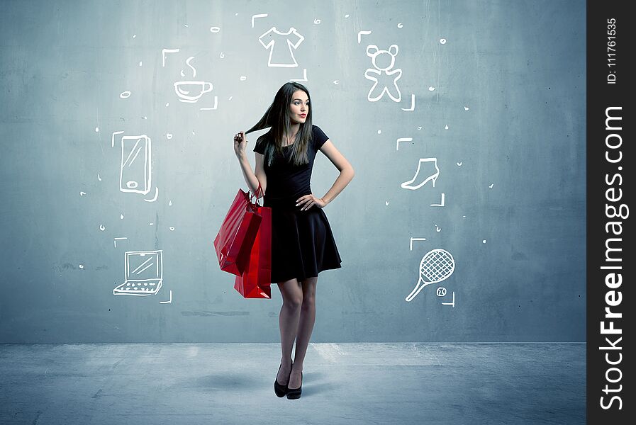 A beautiful young girl in black standing with red shopping bags in front of urban wall background and laptop, shoes, tennis icons concept. A beautiful young girl in black standing with red shopping bags in front of urban wall background and laptop, shoes, tennis icons concept