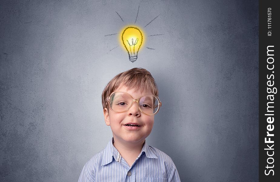 Adorable little kid mull over in front of a grey wall with idea symbol above his head. Adorable little kid mull over in front of a grey wall with idea symbol above his head