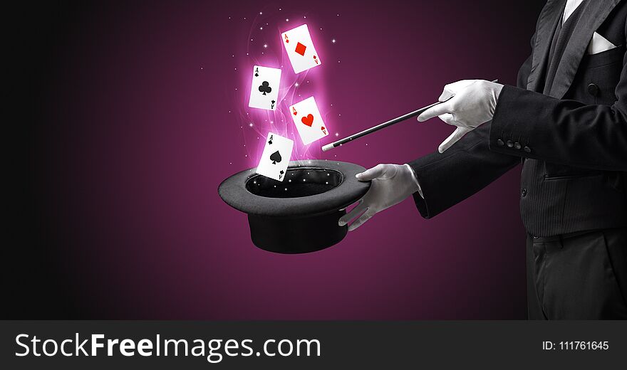 Magician making trick with wand and playing cards