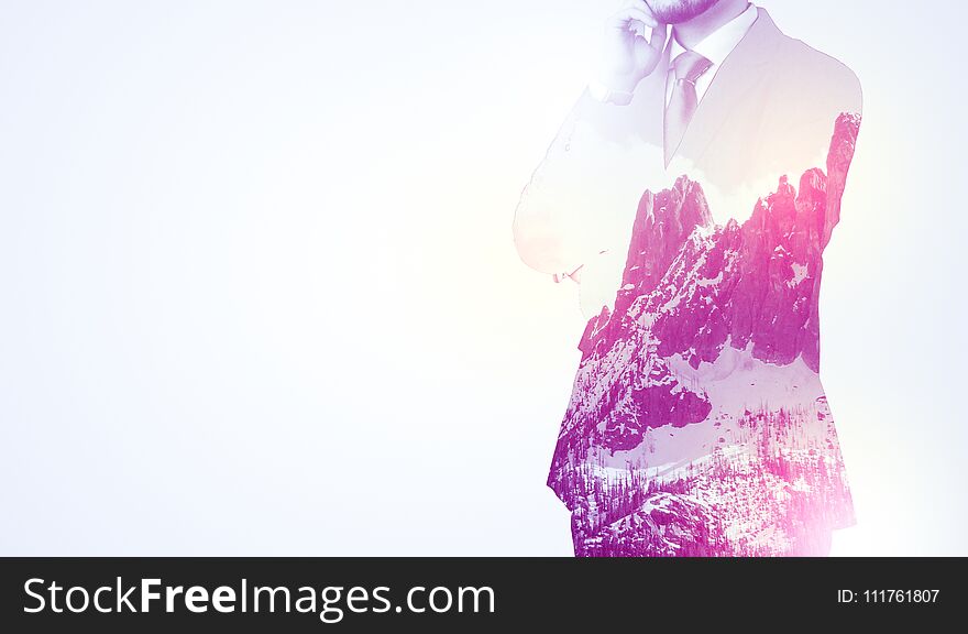 Young businessman in suit standing with sunny snowy mountain and trees graphic. Young businessman in suit standing with sunny snowy mountain and trees graphic.