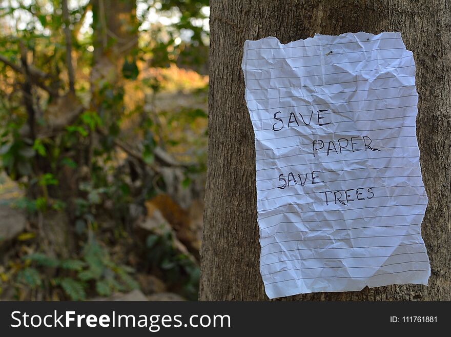 This image consists of save paper save trees note hanging on a tree