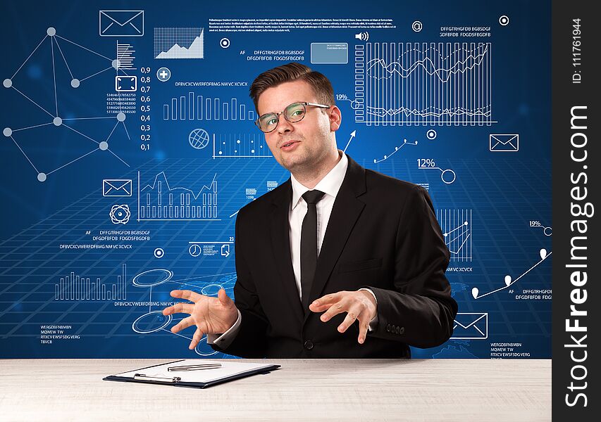 Young handsome businessman sitting at a desk with blue charts and data behind him