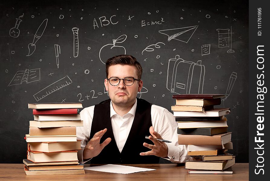 A passionate young teacher sitting at school desk with pile of books in front of blackboard drawn full of back to school items concept. A passionate young teacher sitting at school desk with pile of books in front of blackboard drawn full of back to school items concept.