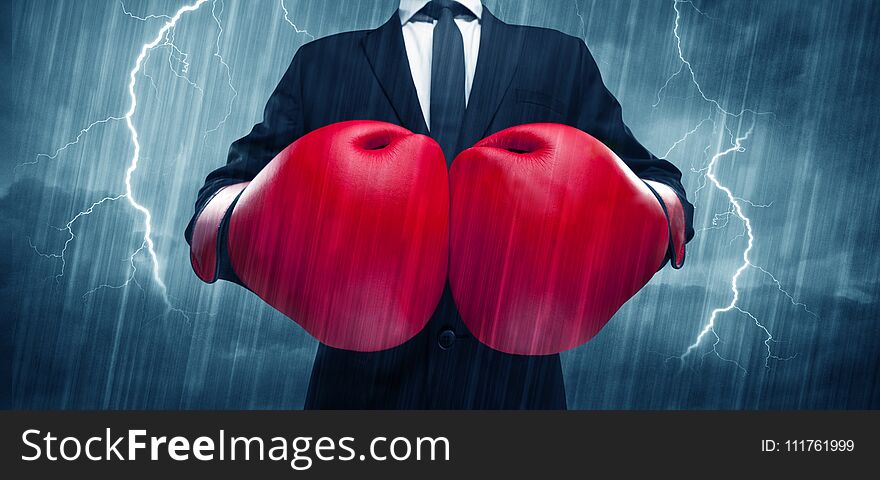 A dangerous sales person getting ready for a fight concept with red boxing gloves and thunder lightning in background. A dangerous sales person getting ready for a fight concept with red boxing gloves and thunder lightning in background.