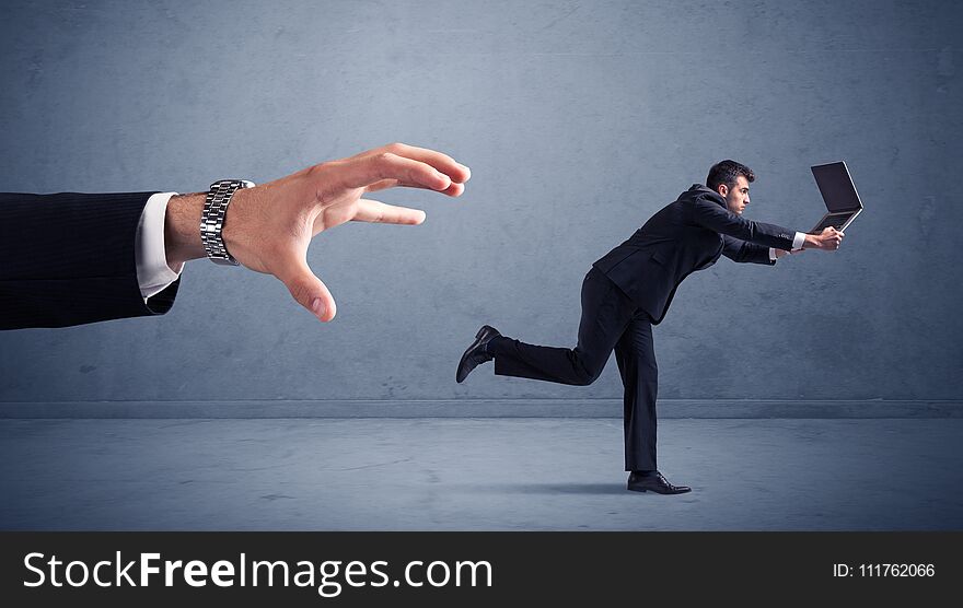 Young miniature businessman running from a big hand with blueish background. Young miniature businessman running from a big hand with blueish background