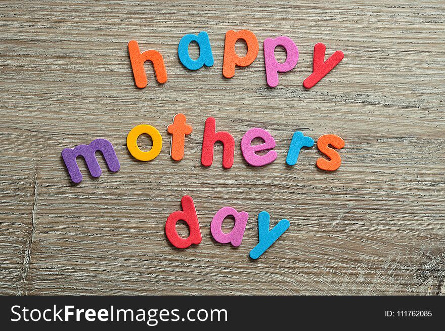 Happy mothers day in colorful letters on a wooden background