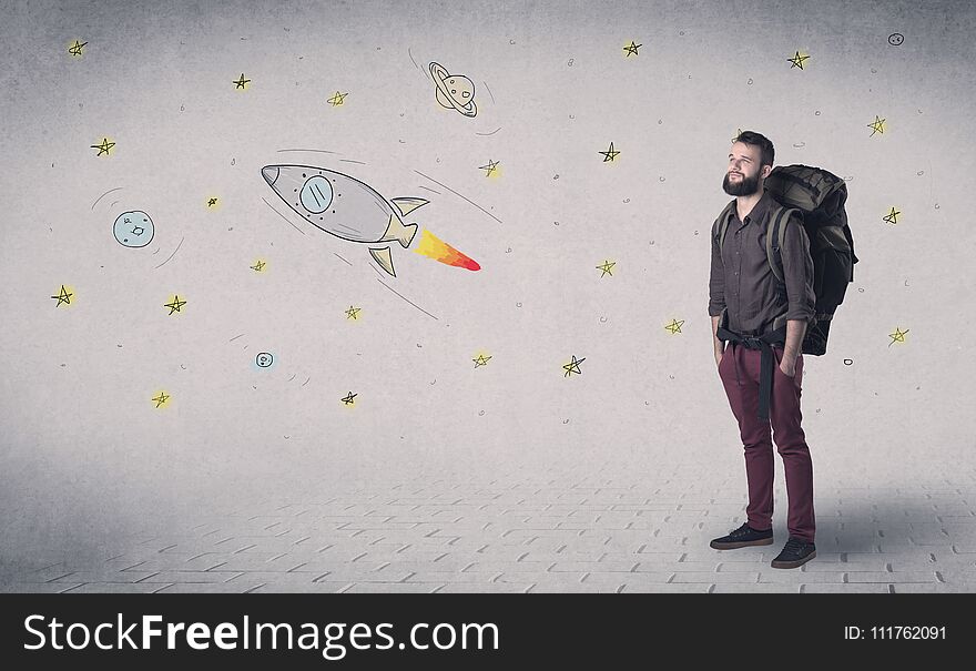 Handsome young man standing with a backpack with space related drawings in the background. Handsome young man standing with a backpack with space related drawings in the background