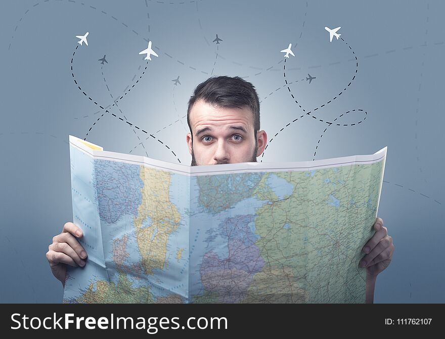 Handsome young man holding a map with little planes and their paths above him. Handsome young man holding a map with little planes and their paths above him