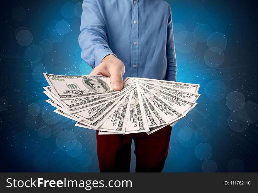 Young businessman holding large amount of bills with shiny blue background. Young businessman holding large amount of bills with shiny blue background