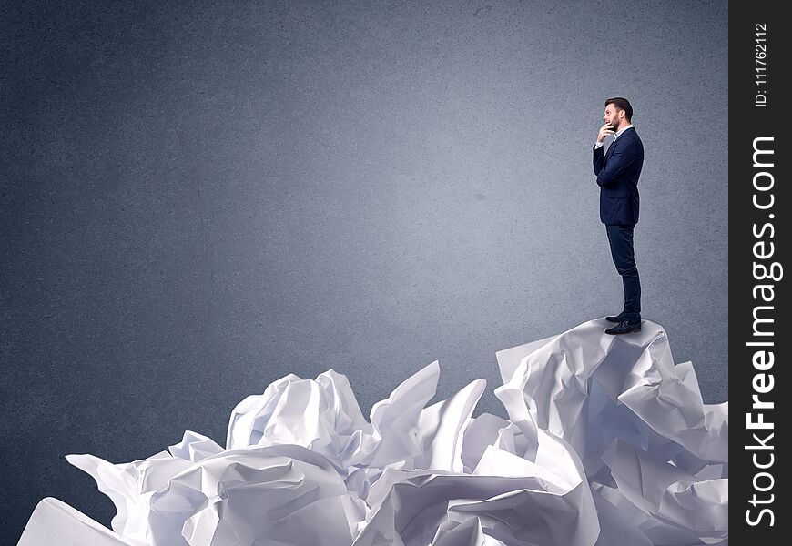 Thoughtful young businessman standing on a pile of crumpled paper. Thoughtful young businessman standing on a pile of crumpled paper