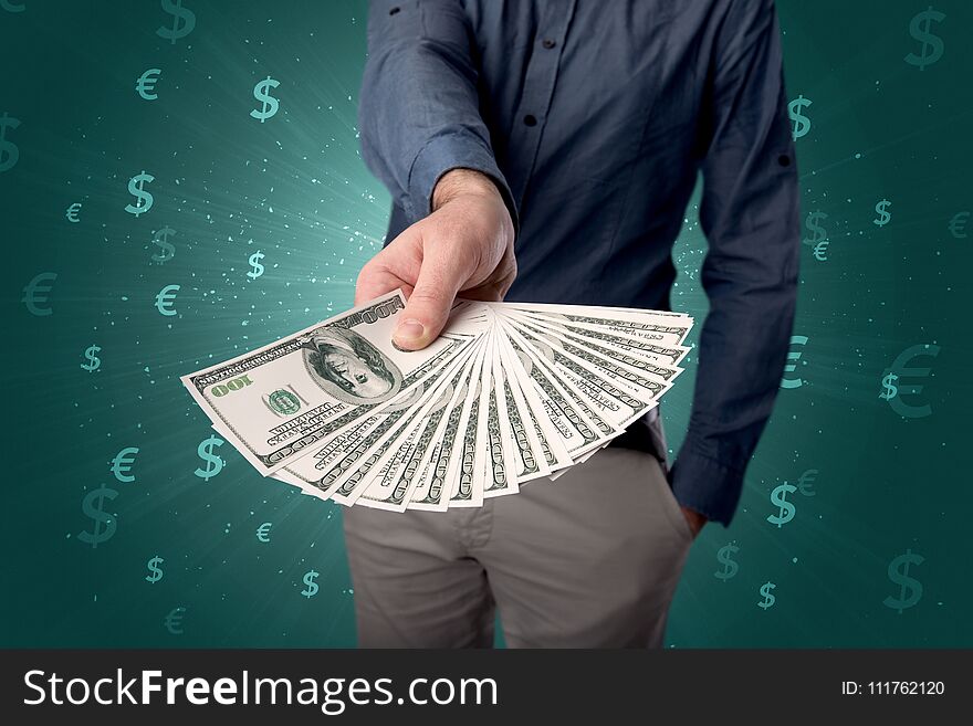 Young businessman holding large amount of bills with green background and currency symbols. Young businessman holding large amount of bills with green background and currency symbols