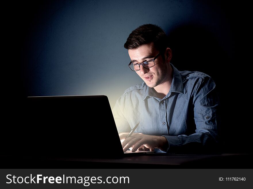 Young handsome businessman working late at night in the office with a dark background. Young handsome businessman working late at night in the office with a dark background