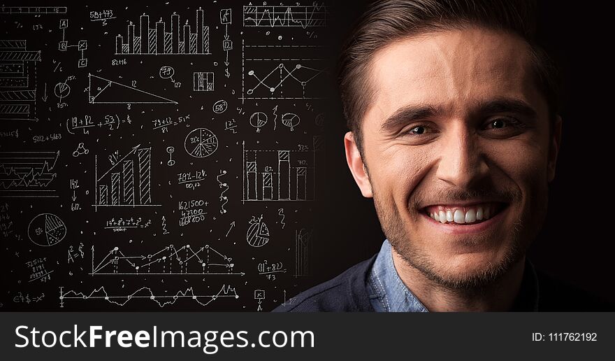 Portrait of a young businessman with charts and graphs scribbled next to him on a dark background. Portrait of a young businessman with charts and graphs scribbled next to him on a dark background