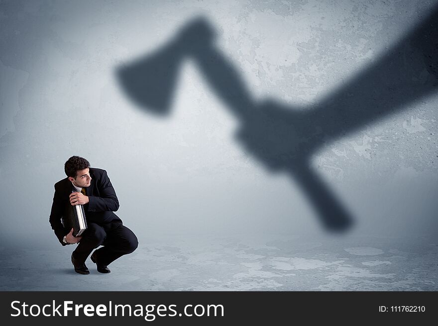 Businessman afraid of a huge shadow hand holding an axe concept on background