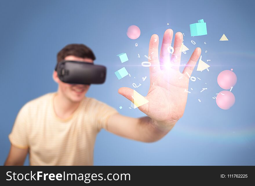 Young impressed man wearing virtual reality goggles with geometric shapes around his hand