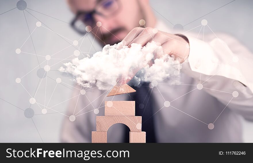 Young handsome businessman using wooden building blocks behind cloud concept. Young handsome businessman using wooden building blocks behind cloud concept