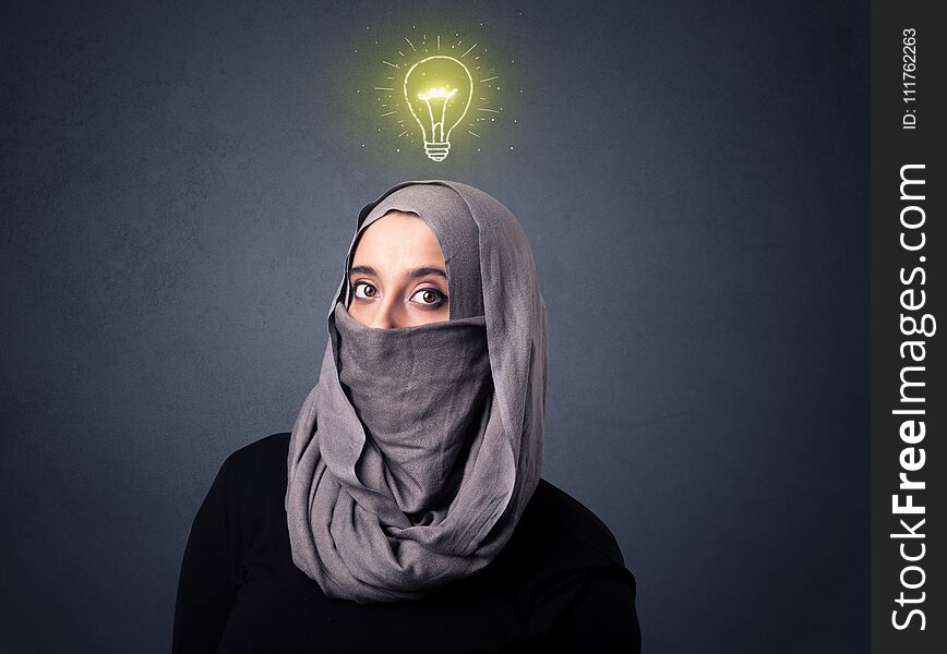 Young muslim woman wearing niqab with lit lightbulb above her head