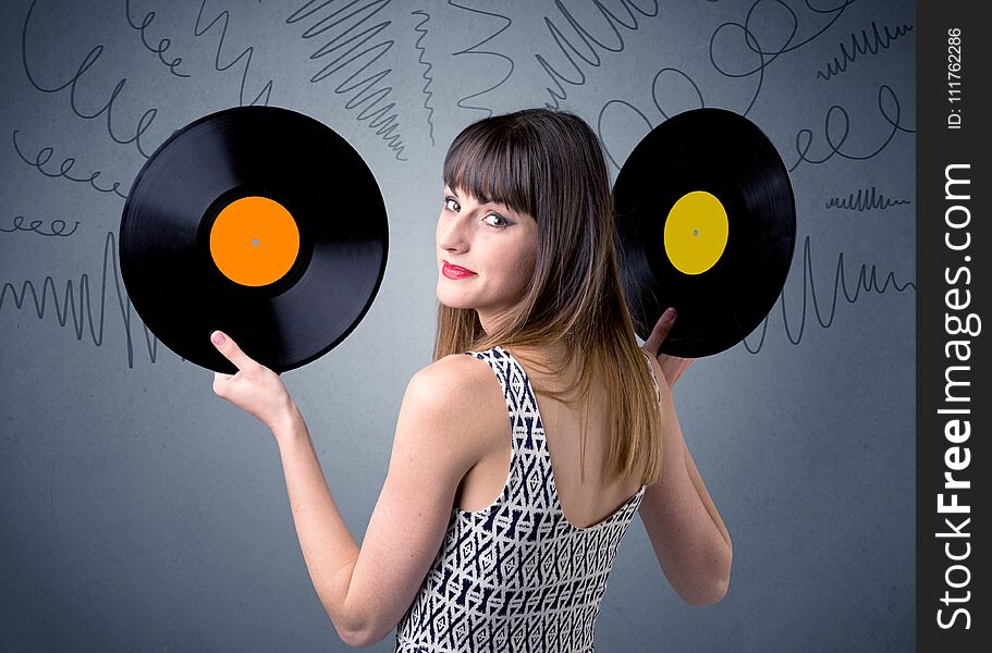 Young lady holding vinyl record on a grey background with scribbles around her