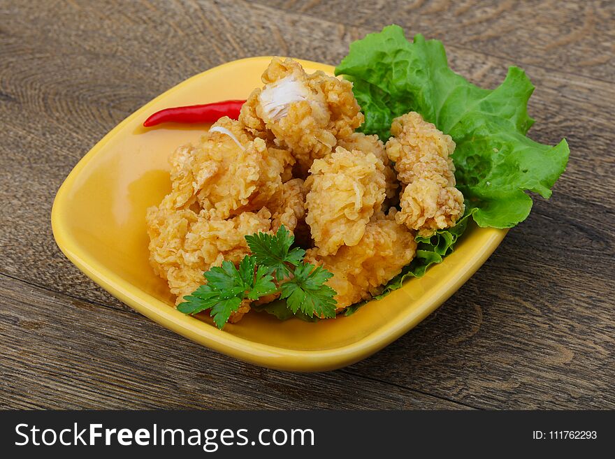 Crispy chicken nuggets with spices on wood background