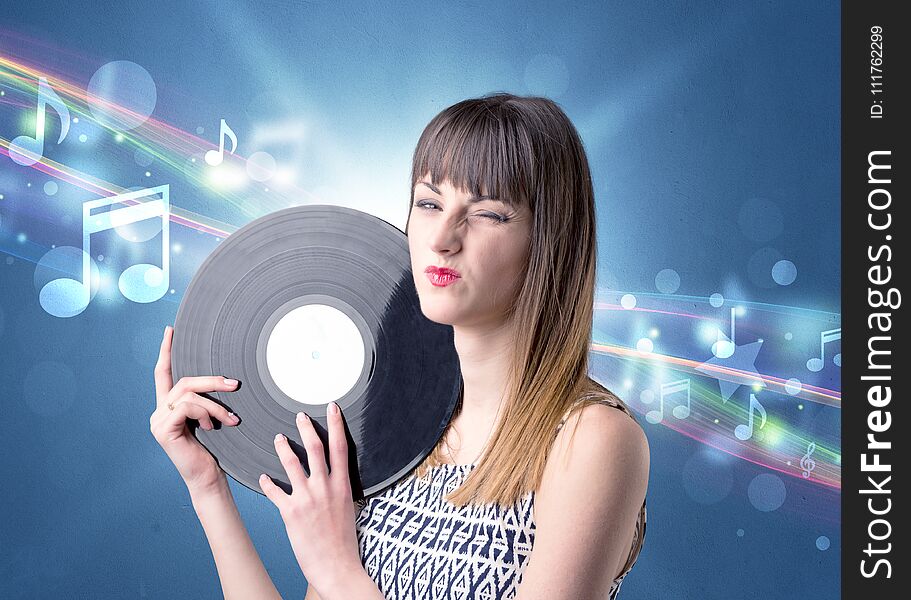 Young lady holding vinyl record on a blue background with musical notes behind her