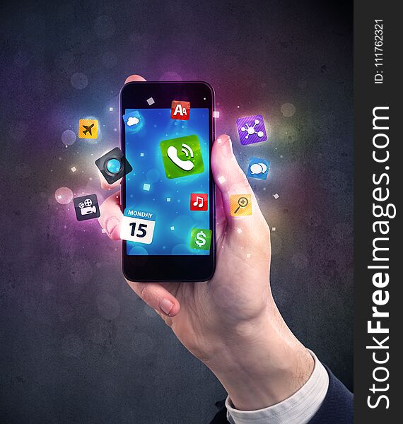 Caucasian hand in business suit holding a smartphone with colorful media icons. Caucasian hand in business suit holding a smartphone with colorful media icons