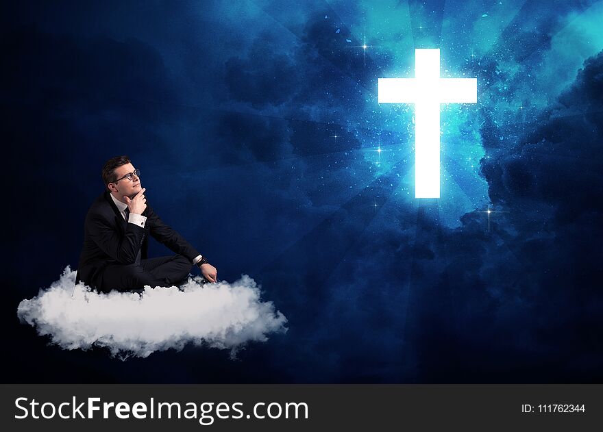 Caucasian businessman sitting on a white fluffy cloud looking and wondering at a big bright glowing cross. Caucasian businessman sitting on a white fluffy cloud looking and wondering at a big bright glowing cross
