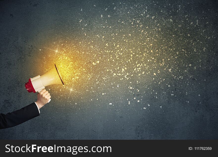 Caucasian business hand holding megaphone with yellow sparkles