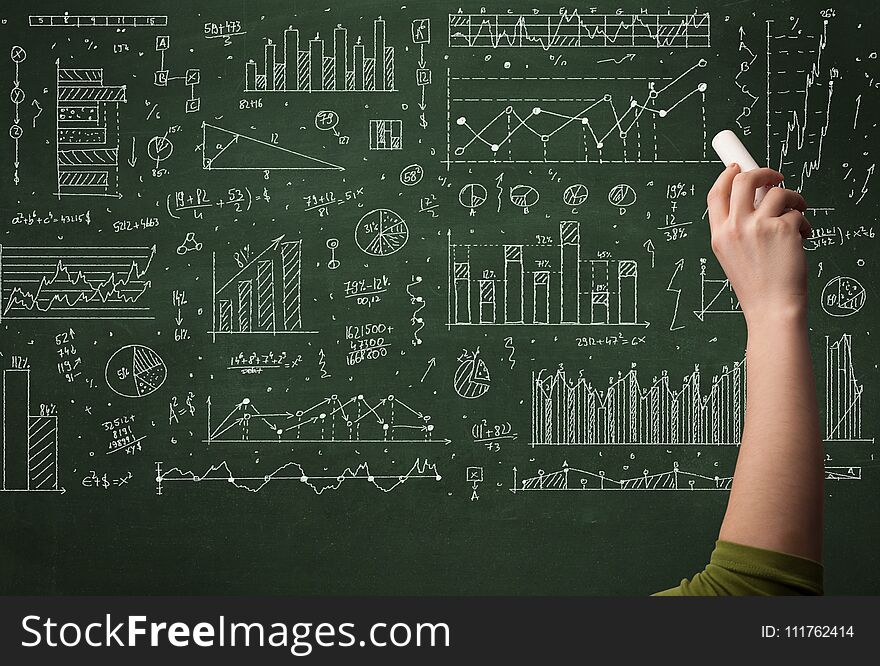 A hand drawing lines, pie charts, graphs on a green blackboard with a chalk. A hand drawing lines, pie charts, graphs on a green blackboard with a chalk