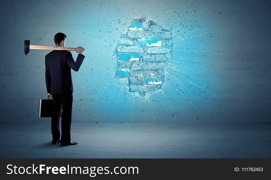 Business man hitting grungy brick wall with huge hammer