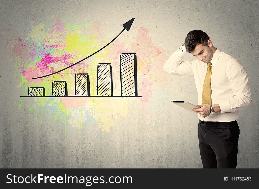 An elegant businessman standing in front of a grey wall with colorful growing chart drawing concept. An elegant businessman standing in front of a grey wall with colorful growing chart drawing concept