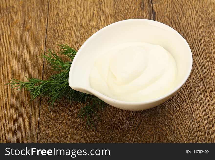 Greek yoghurt with dill leaves on wood background