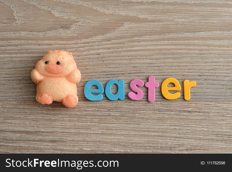 A chicken shape marshmallow with the word easter isolated on a wooden background