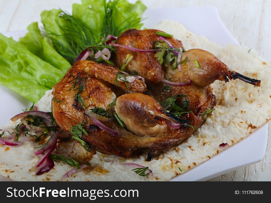 Grilled quail with onion and salad leaves