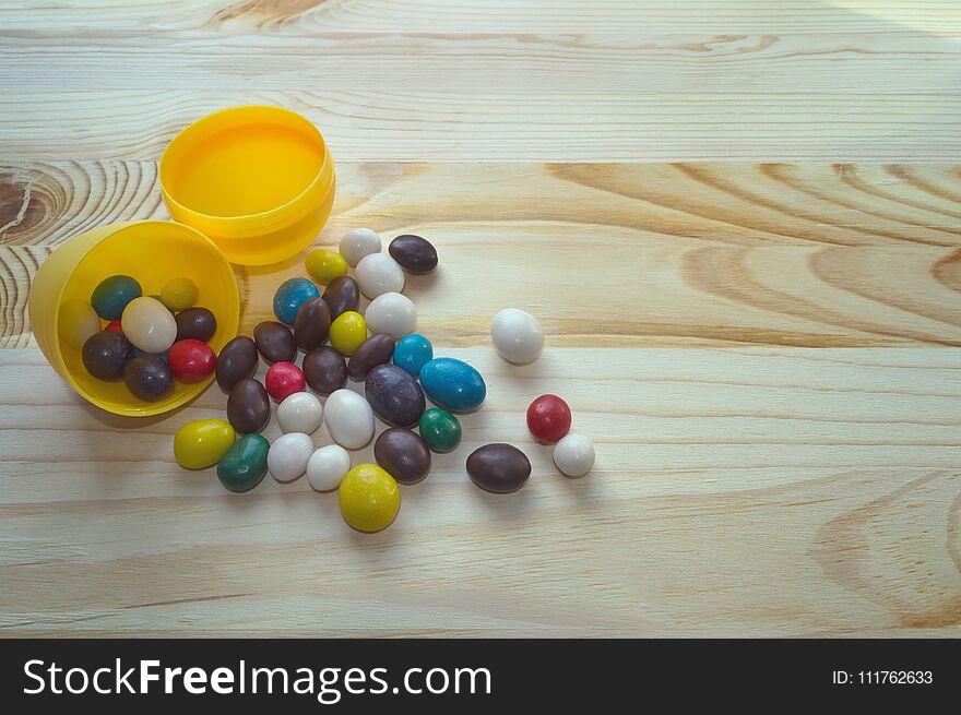 Colorful candies scatterred from egg shell on wooden background