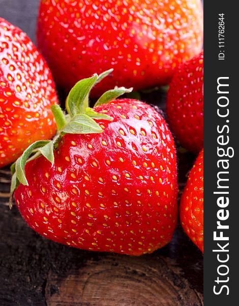 Sweet and fresh strawberry on dark background. Natural food. Vertical. Close-up.