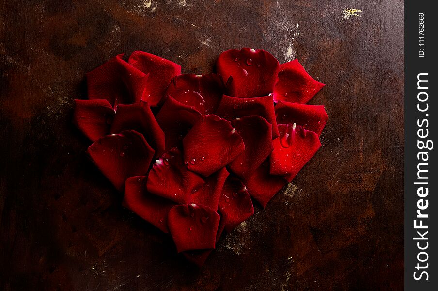 Top view flat lay red rose petals in heart shape on dark background. Romance, passion concept. Valentines day