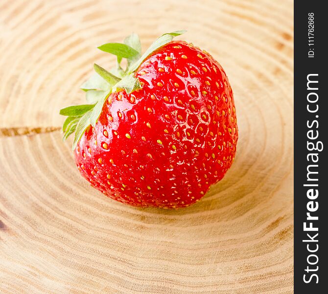 Sweet and fresh strawberry on light-brown stump background. Natural food. Square. Close-up.