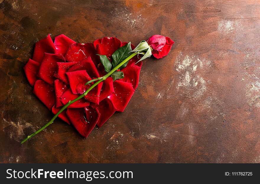 Top view flat lay red rose petals in heart shape on dark background. Romance, passion concept. Valentines day. Text space