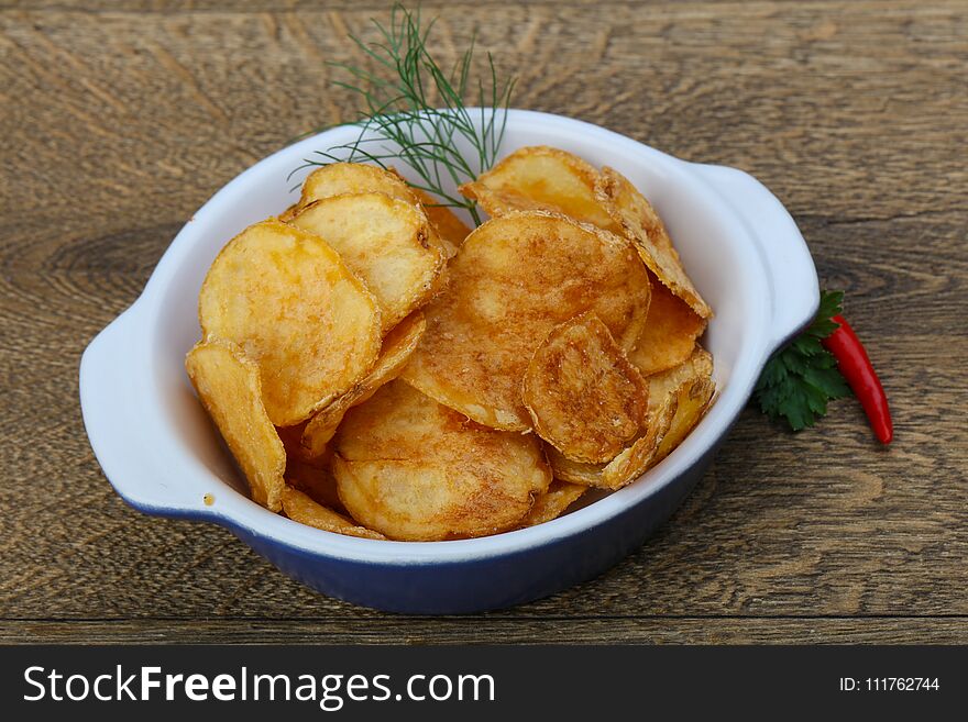 Natural potato chips heap in the bowl on wood background