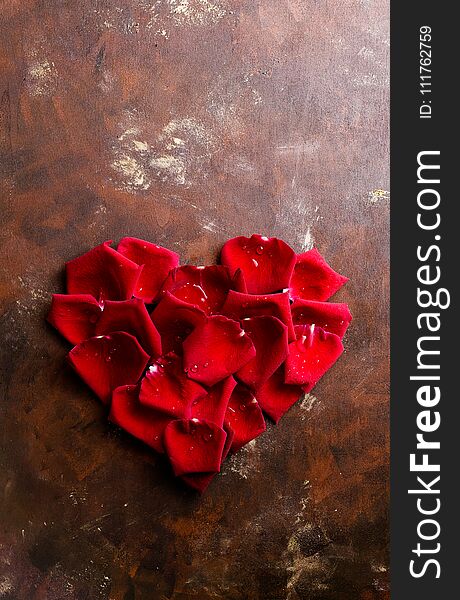 Top view flat lay red rose petals in heart shape on dark background. Romance, passion concept. Valentines day