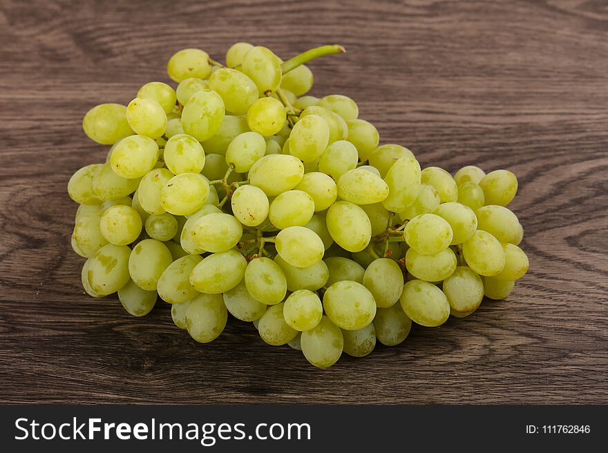 Sweet yellow grape heap on the wood background