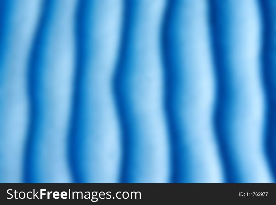 Blue sand texture. Background with Light blue fine sand. Sharp lines of waves on sand. Sand surface on the beach, view from abov